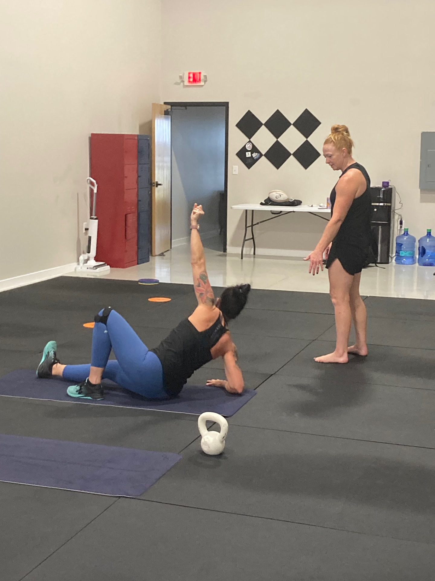 Coach guiding a member through the Turkish get-up elbow position at Liberty Bells