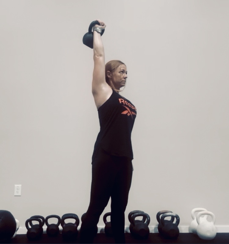 Coach locking out a one-arm kettlebell press overhead at Liberty Bells