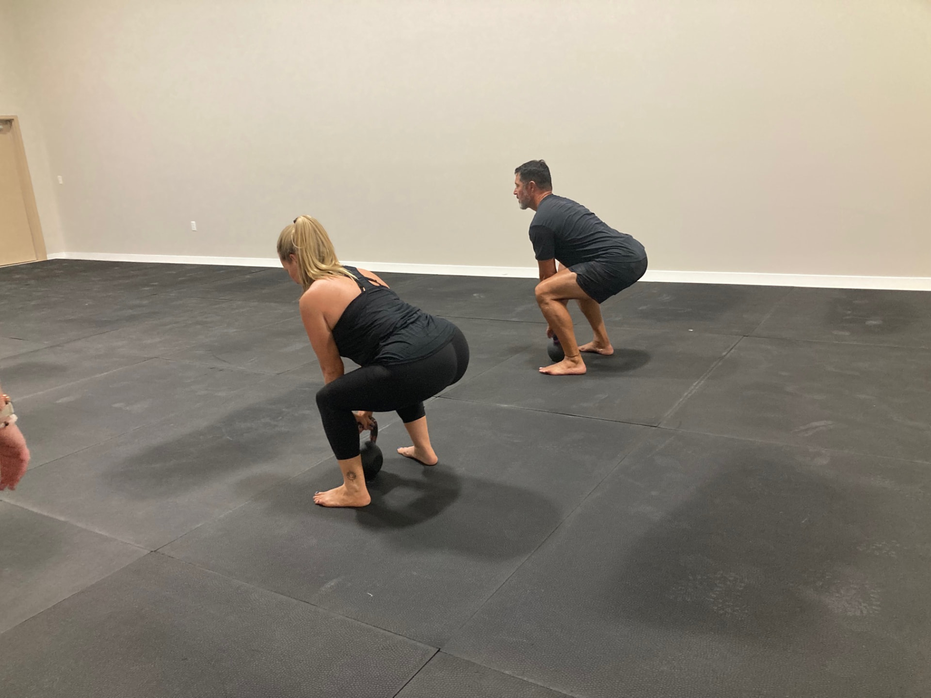 Two members hinging into kettlebell deadlifts during class