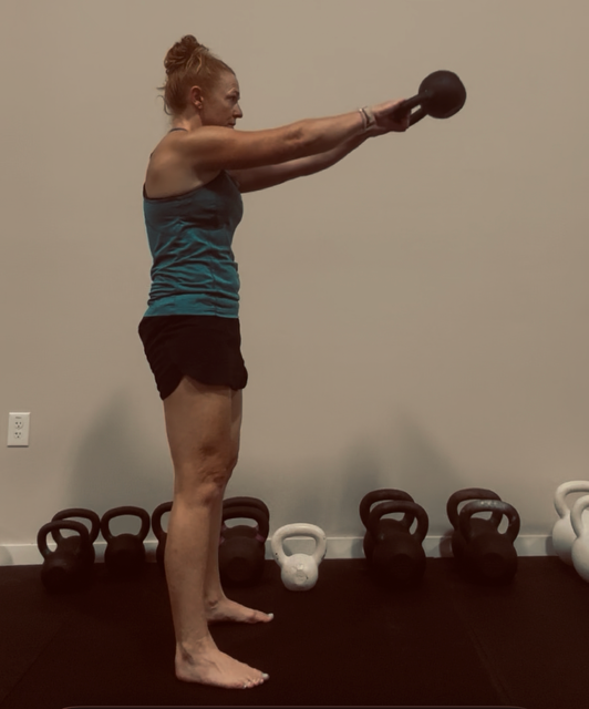 Standing tall and braced at the top of a kettlebell swing — the plank position